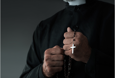 Priest holding rosary beads in hands.