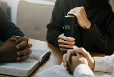 People praying with Bibles at table.