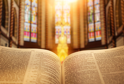 Open book in front of stained glass.