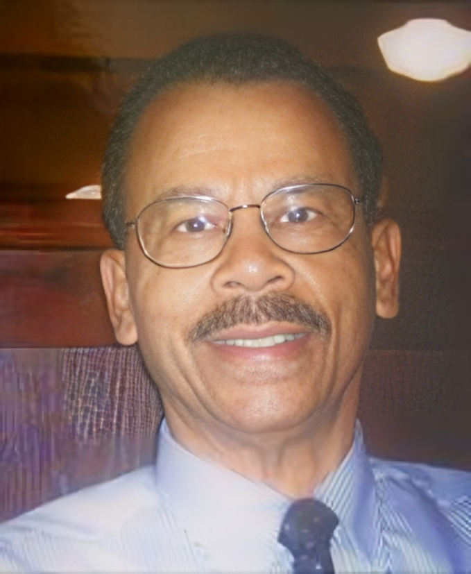 Smiling man wearing glasses and blue shirt.